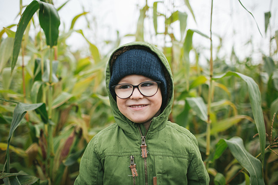 Young boy with glasses standing outside