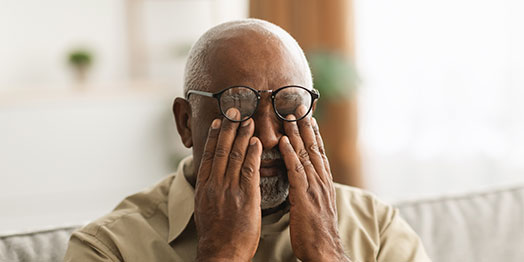 Man suffering from glaucoma rubbing his eyes 