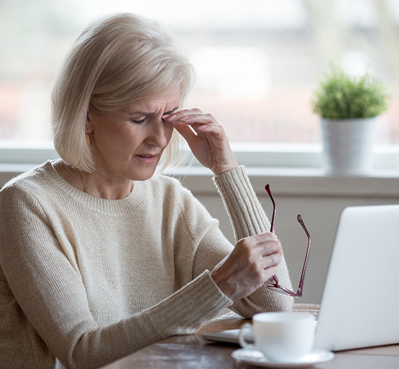 Woman working on laptop suffering from dry eye symptoms